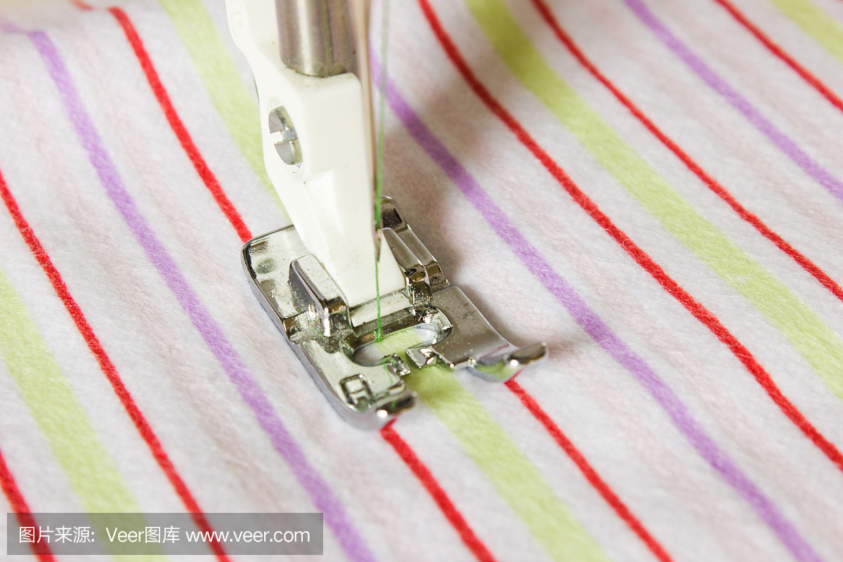缝纫机脚的特写在一块条纹布上。